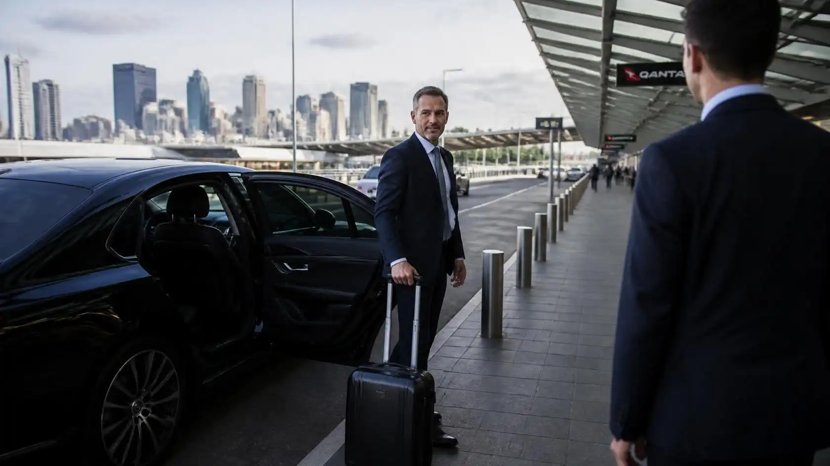 Executive chauffeur Melbourne holding the door of a luxury sedan for a business passenger
