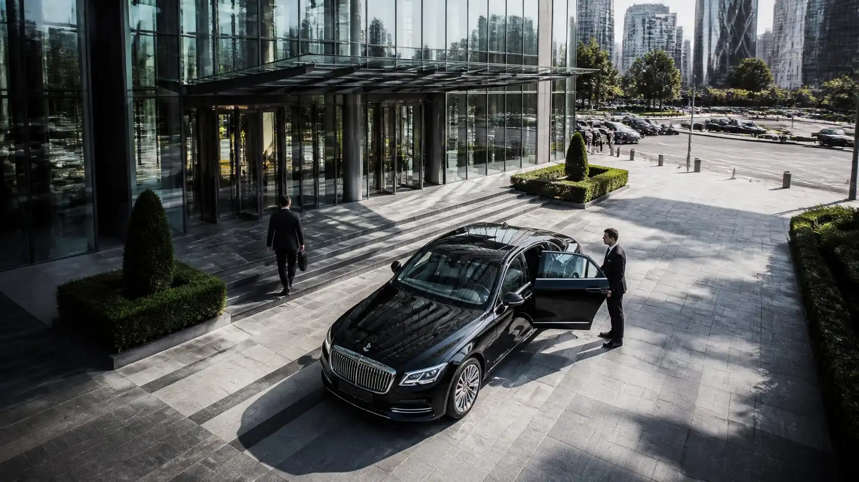 Corporate chauffeur Melbourne greeting an executive beside a luxury sedan at a city office